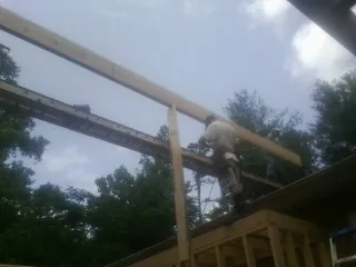 Carpenter setting a ridge beam over a new addition frame — Ice Dam Removal by Roofing Brothers in Olmstead