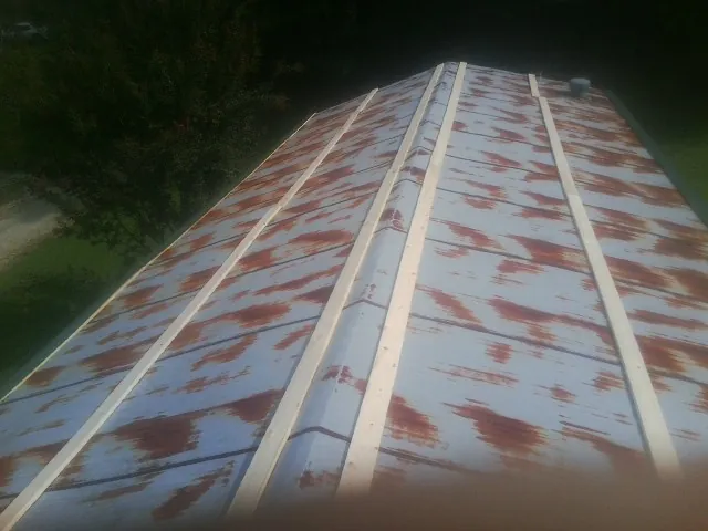 Rusted metal roof panels with new wood purlins before replacement — Storm Damage Roof Repair in Olmstead by Roofing Brothers