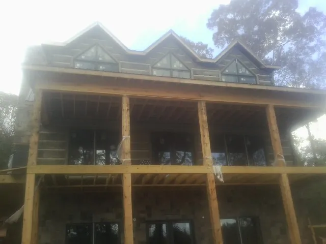 Dormers and porch framing on a large log home under construction — Roof Coating work by our crew in Olmstead