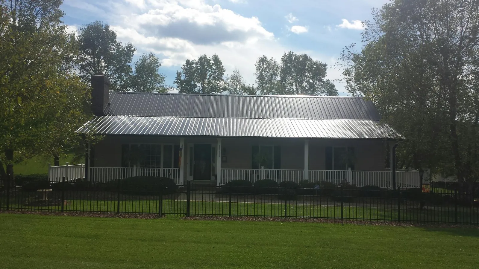 Gray metal roof on a brick ranch with a full width front porch — Gutter Guard Installation work by our crew in Olmstead