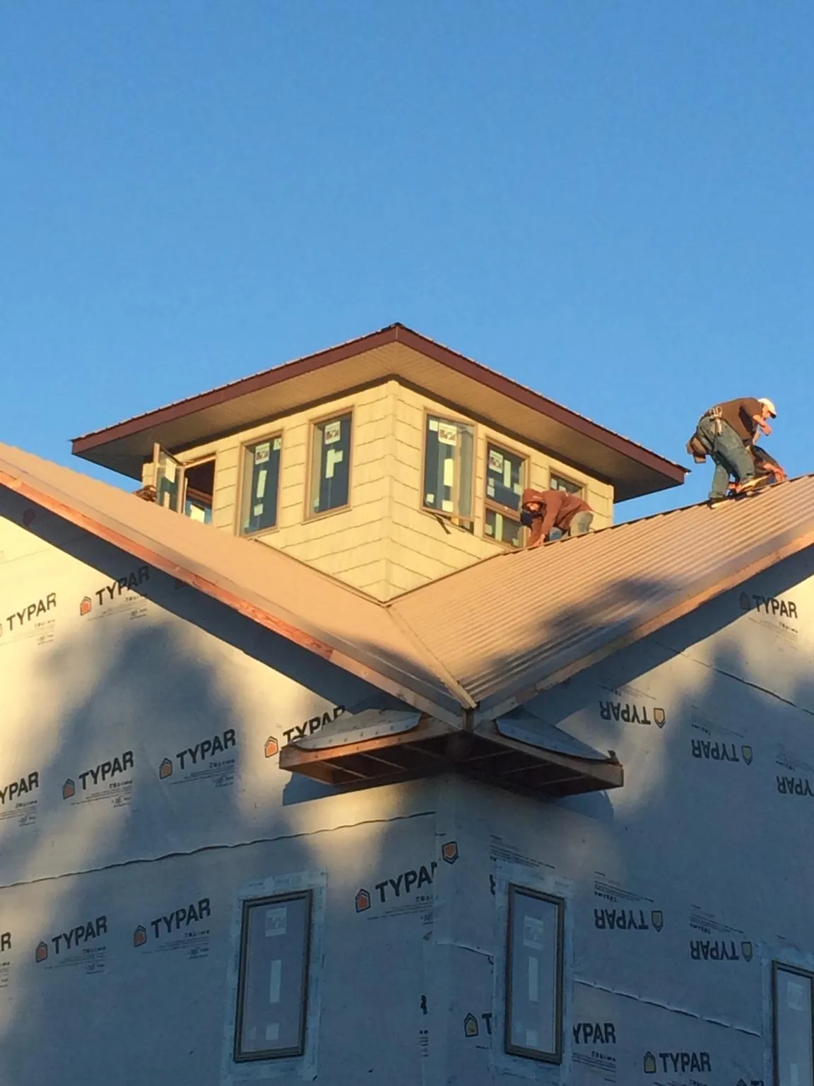 Roofers working around a rooftop cupola on a new metal roof at sunset — Roof Waterproofing in Olmstead by Roofing Brothers